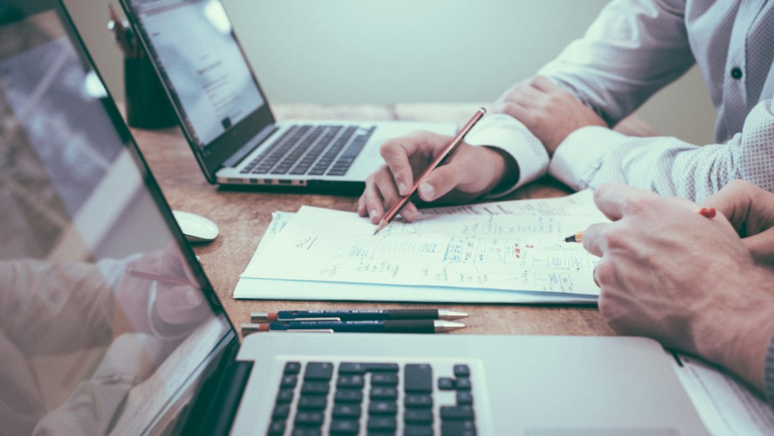 Professionals reviewing financial paperwork beside laptops
